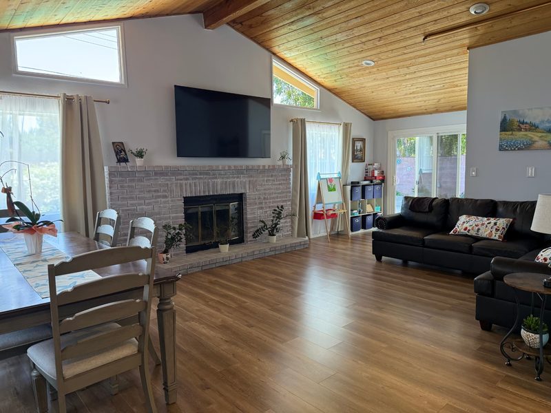 Spacious high-ceiling living room with fireplace and dining area at Aurora Senior Living Napa