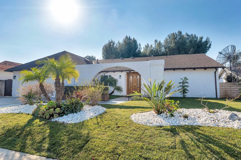 Sunny front lawn, palm trees and arched entryway at Aurora Lemarsh senior living home in Chatsworth